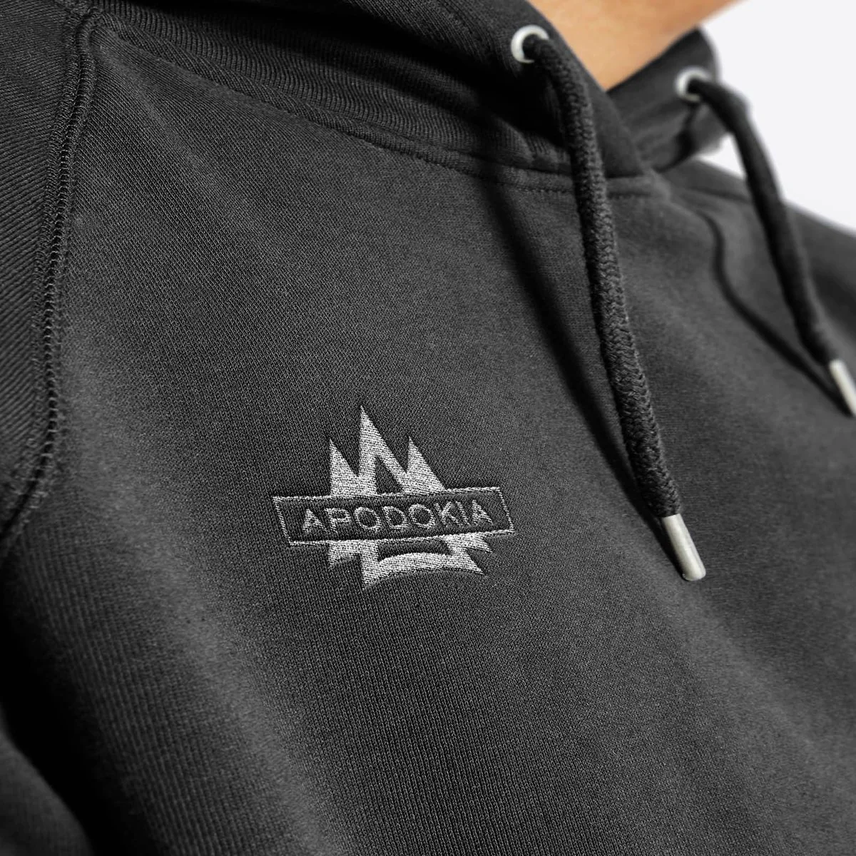 Close-up of the APODOKIA logo embroidered on a black hoodie