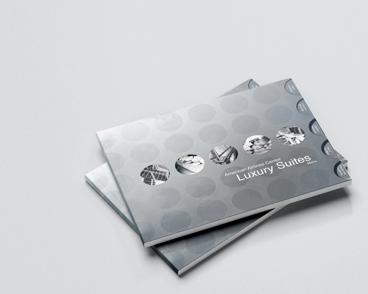 Two American Airlines Center Luxury Suites menus: silver covers with a row of five die-cut circle windows and round index tabs
