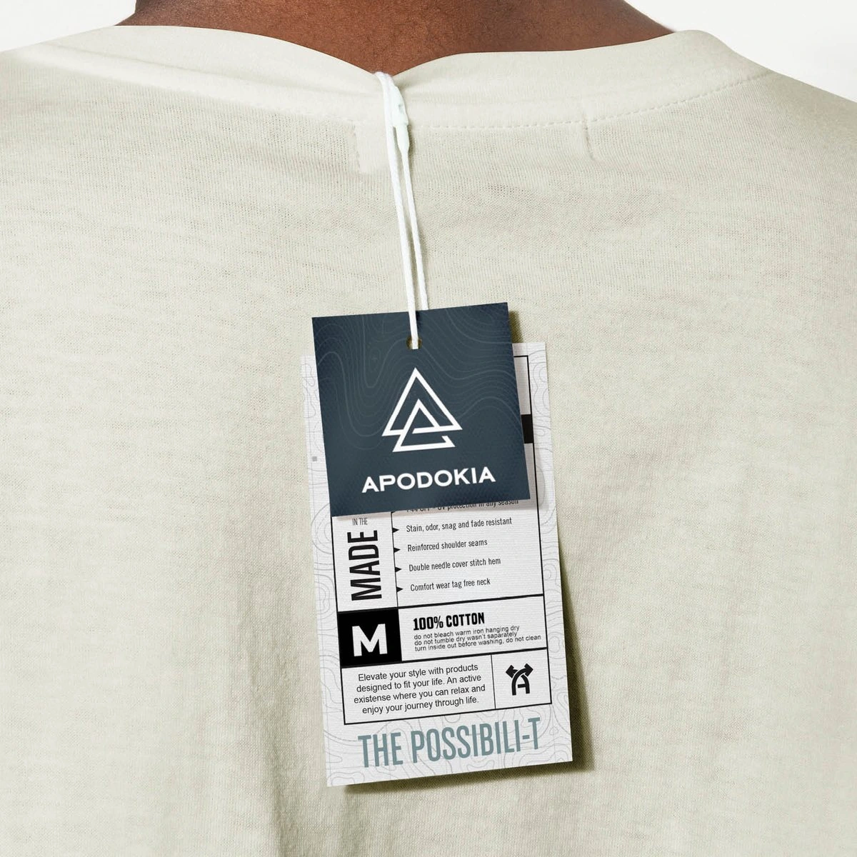 APODOKIA hang tag on the back of a cream T-shirt, labelled “The Possibili-T”