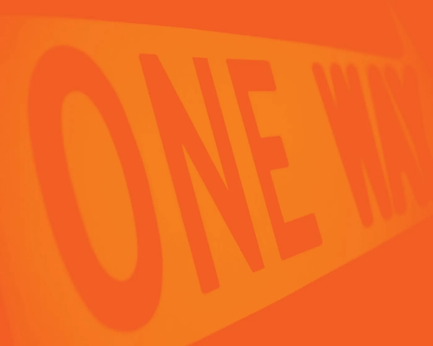 Close-up of a ONE WAY sign in tones of safety orange